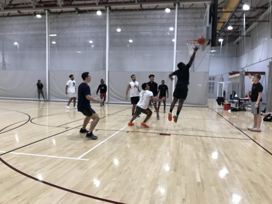 After a missed shot, a player attempts to jump up and rebound the ball off the backboard. Most players take a lot of pride in these intramural games as it gives them the opportunity to show off their skills in basketball.