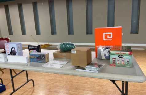 A table with the winning prizes displays. The prizes includes outdoor pack, snacks and hammock, gaming headset, wireless speaker and an Apple watch series 7. 