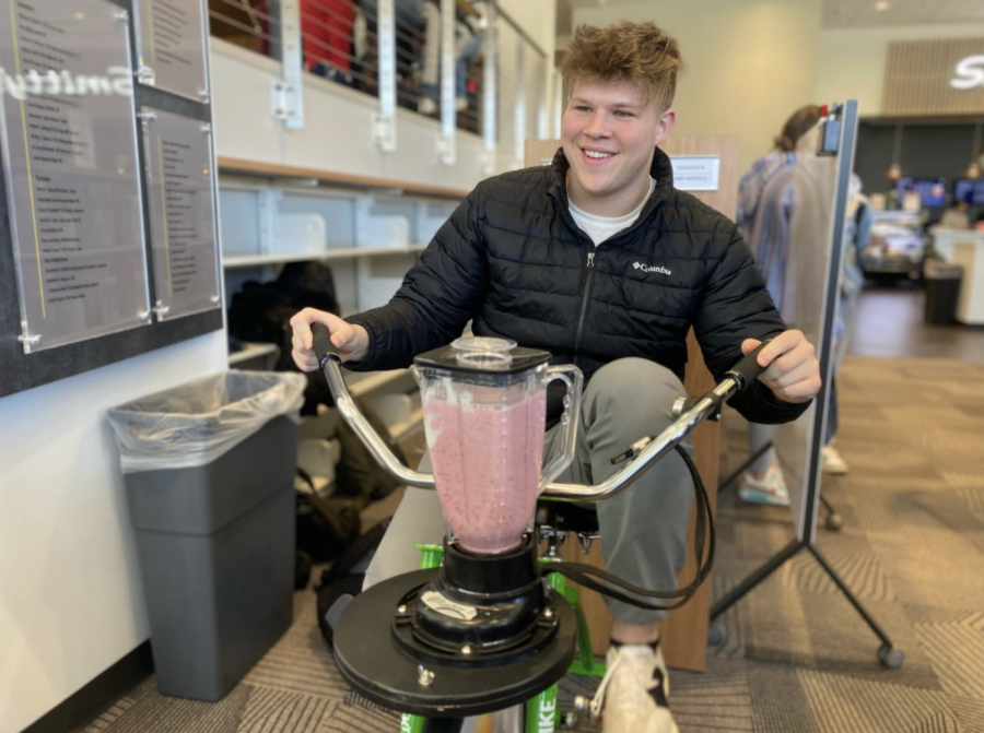First-year Andrew Hall peddles a bike at the Farmer’s Market to make a smoothie.