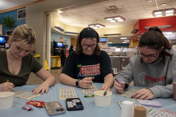 Three friends partake in a match of bingo. This showcases the camaraderie the game brings out in everyone, as well as the competitiveness.