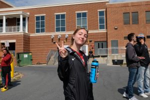 Senior Mackenzie Young throws up a peace sign for a picture. Young competed in the steeple.