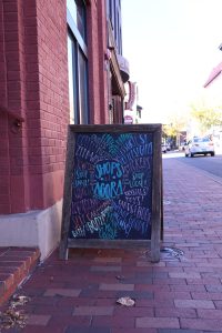 A sign welcomes guests to the Agora Downtown Market, also known as the Shops at Agora, located on South Main Street in the heart of downtown Harrisonburg. The marketplace features a community of small, local businesses including Great.Full Goods, Lineage, Bougie Hippie, Heartworn Vintage, Broad Porch Coffee Co. and more!