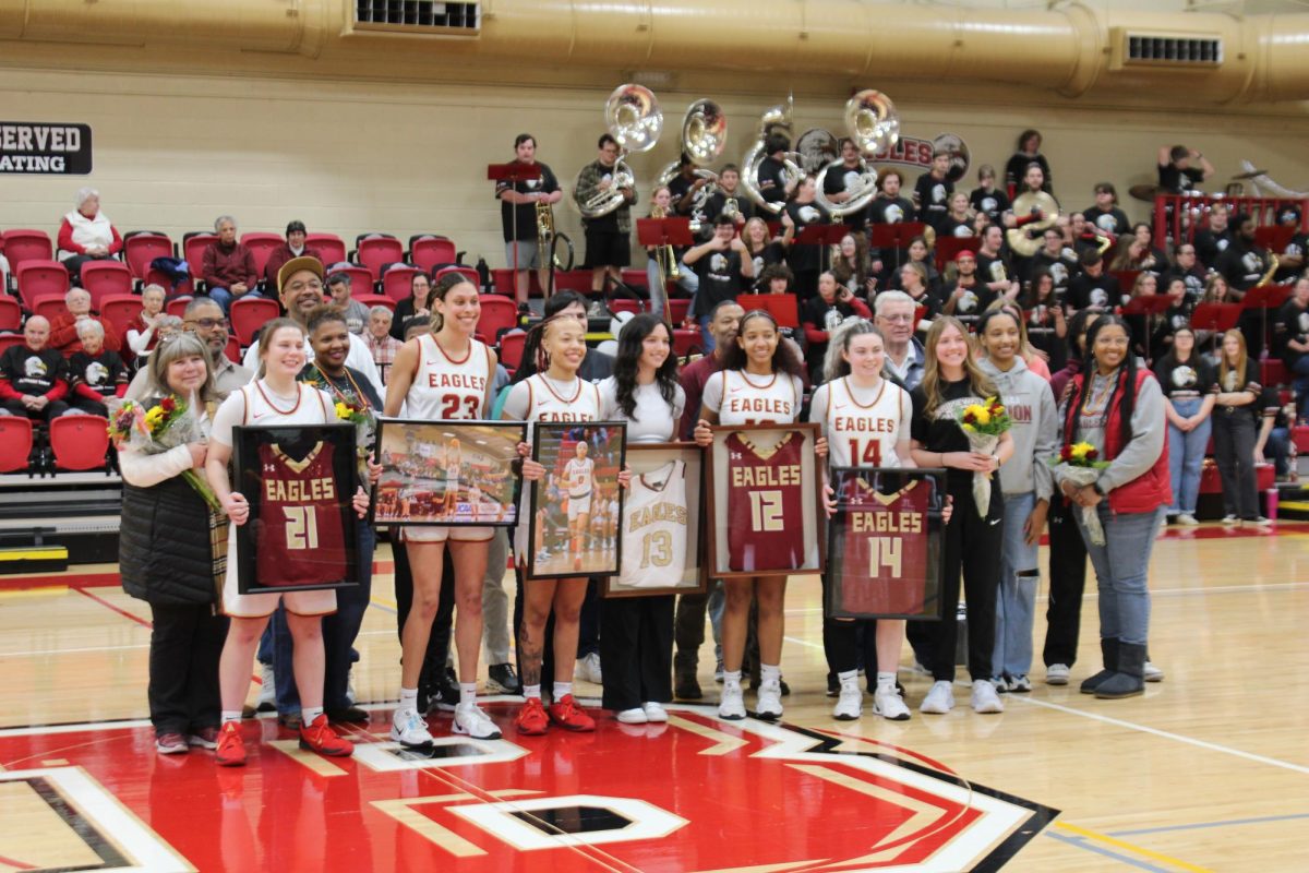 Bridgewater seniors smile with loved ones holding framed jerseys, flowers and action shots. From left to right is number 21 Rosemary Pierson, number 23 Jaden Alsberry, number 0 India Dailey, number 13 Reagan Maynard, number 12 Alexis Edmonds and number 14 Alexis Woods.