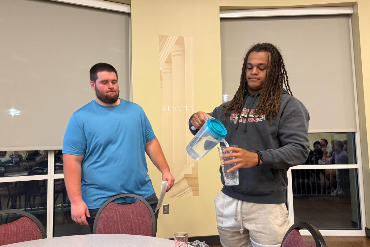 Senior Collin Nicholson (left) has volunteer junior Kyle Galloway (right) demonstrate how much a shot of liquor is. It is important for students to acknowledge what a standard shot of liquor looks like. 
 