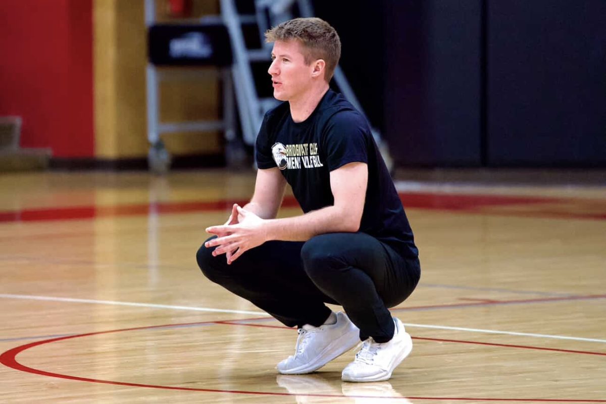 Assistant Men’s Volleyball Coach Nolan Hurrell crouched down talking to his athletes during practice. This photo was taken during one of their early morning practices. Photo by McKenna Curry.