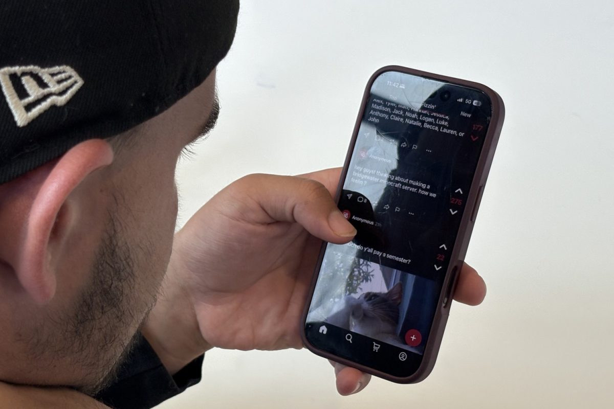 Noah Hess, a Fizz user and student at BC, poses as he scrolls through the Fizz app. Hess is among the active posters on the app but maintains concerns about negativity on the app.