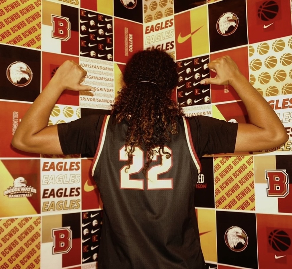 Jay Garcia shows off her #22 jersey against Bridgewater’s media day backdrop. The image reflects her confidence heading into her coaching journey.
