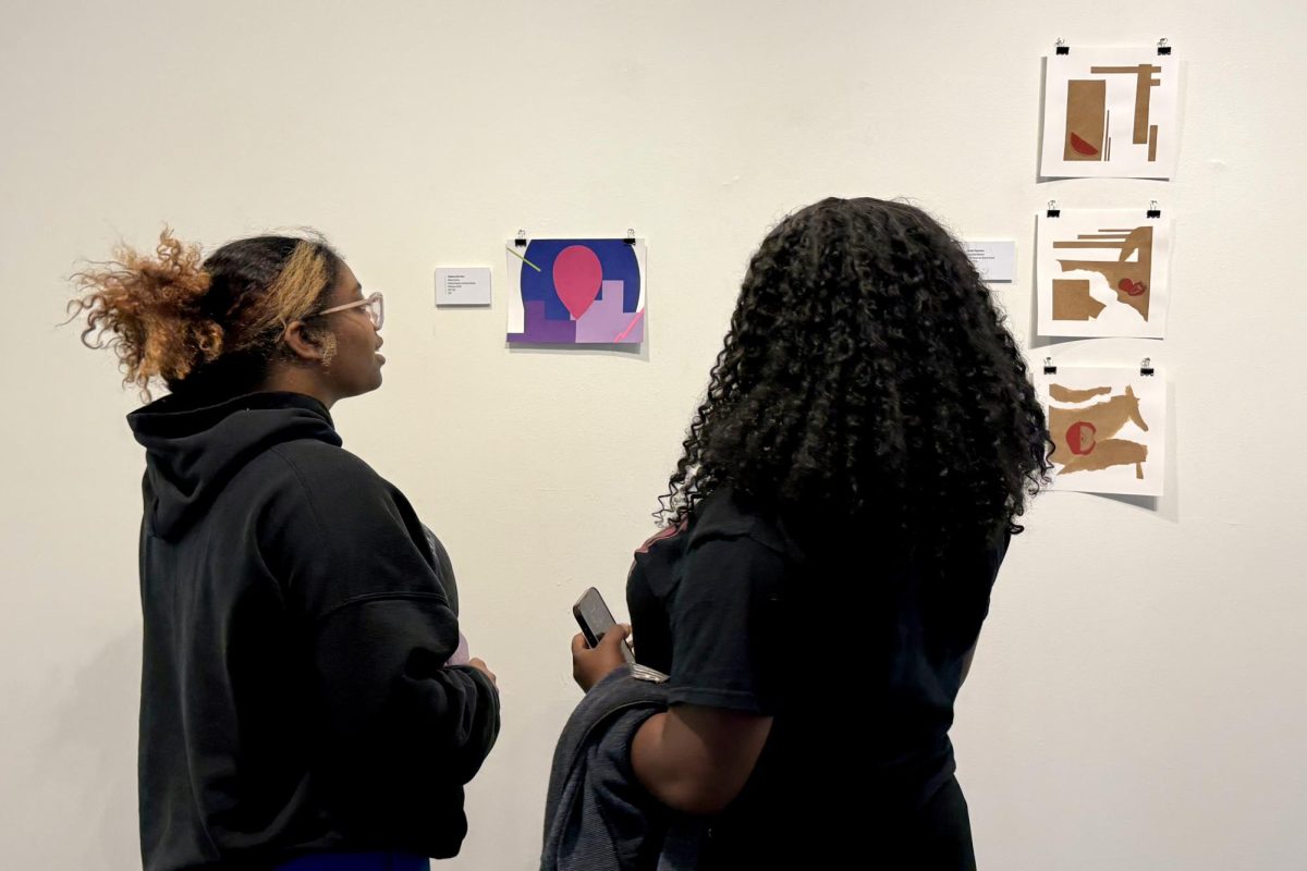 Two visitors pause in front of works displayed in the juried student art show. These works were done by students in both creative and non-creative majors. 