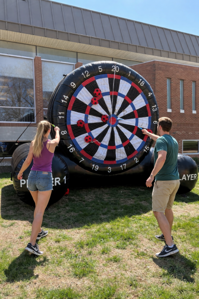 Students participate in a pop-up campus activity, playing an inflatable dart game outside by the campus mall. This was part of the 10th anniversary of "Day of Giving", where activities were set up by student life to encourage student engagement