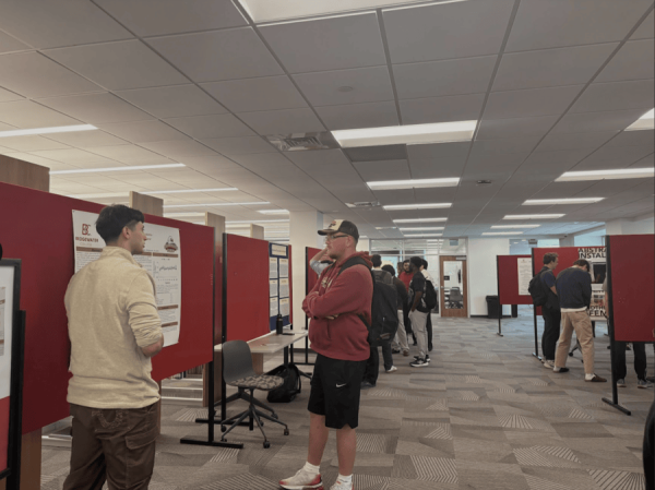 Students walk through the FLC viewing research posters. The displays highlight student work presented during the week. 